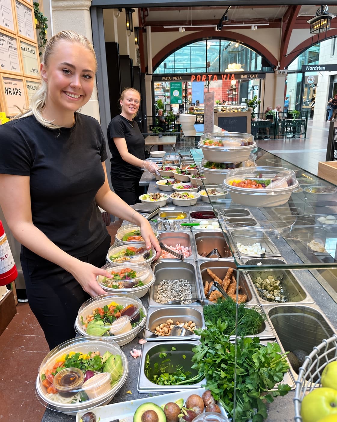 Två kollegor förbereder sallader bakom disken på Togogo Centralen