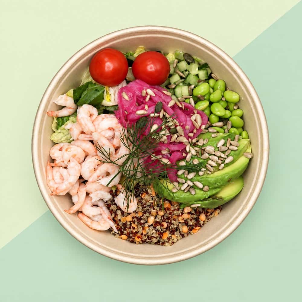 Räksallad med avokado och grönsaker på diagonalt delad grön bakgrund